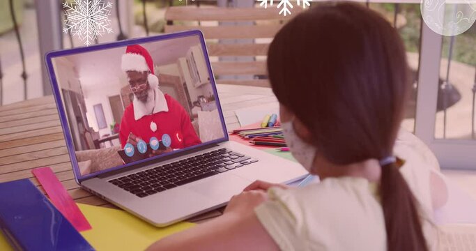 Animation of snow falling over girl with face mask on laptop video call with santa at christmas