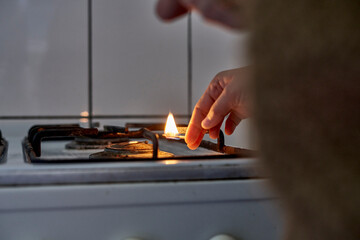 Woman trying to turn on gas with a match flame. Female hand trying to turn on old gas stove. No...
