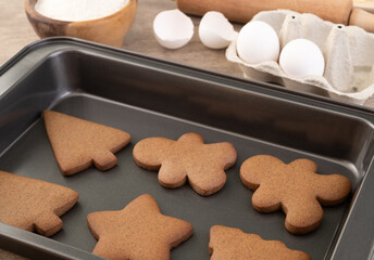 Traditional christmas gingerbread cookies over a wooden table with ingredients