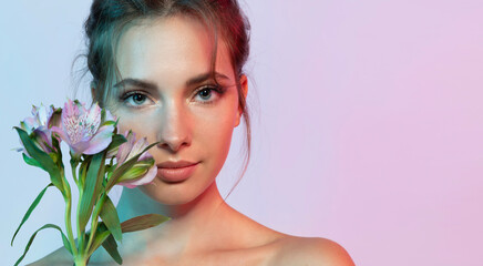 Beautiful girl with perfect clean skin and natural make-up looking at camera with flowers.
