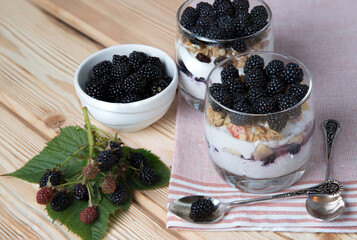 Blackberry berries in a summer dessert - cheesecake in glasses on a wooden background. Healthy snack