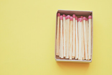 Matches in an open box on a yellow paper table. Copy space