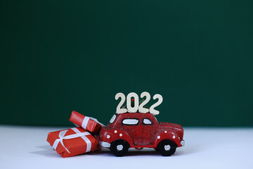 A red car with the numbers 2022 on the roof carries New Year's gifts. New Year in the car showroom.