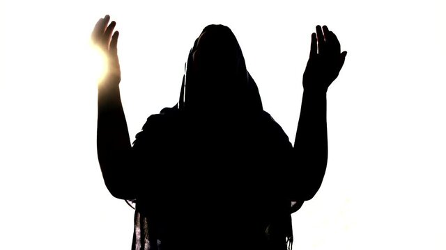 silhouette of woman praying in front of light