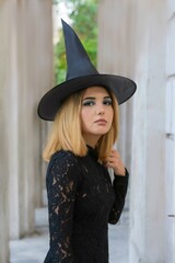 Young witch in black dress and cap halloween all saints day free space for text