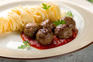 Spaghetti with meatballs and tomato sauce on plate close up