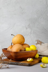 Chinese nashi pears and quince in a wooden bowl. Vertical frame on a gray background, close-up, vertical