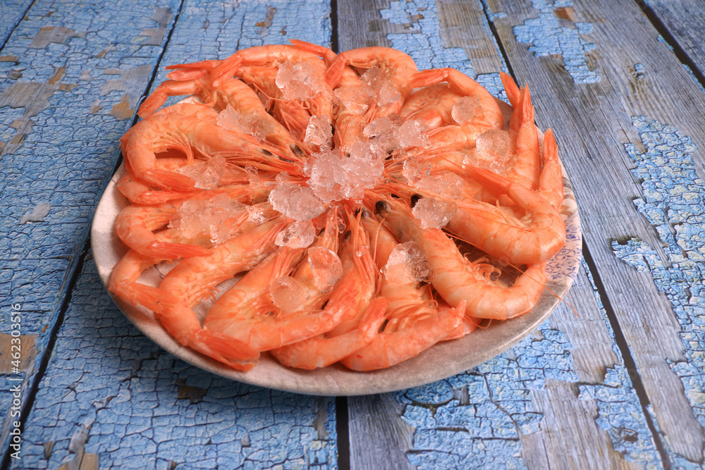 Wall mural portion of cooked white prawns from huelva on blue old wooden background