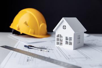 Construction plans with helmet, house and drawing tools on a table