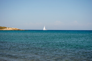 White boat sailing in the open blue aegean sea in Greece