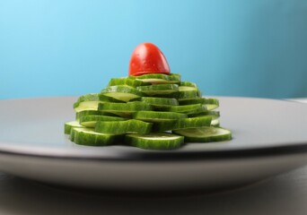 edible Christmas tree of cucumbers and tomatoes of vegetables on a gray plate on a blue background. Festive atmosphere