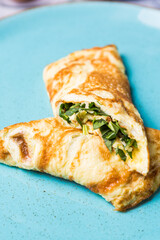 Egg omelet stuffed with greens on a blue plate. beautiful omelette for your menu