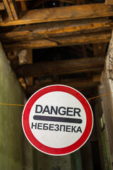 Old wrecked house with 'Danger' in English and in Ukrainian warning sign, abandoned building, uninhabitable place
