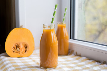 Pumpkin juice in a bottle light background, two bottles, pumpkin on the windowsill