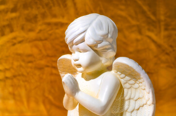 White angel boy sculpture near the firelight with golden shadows on the body. Close-up scene...