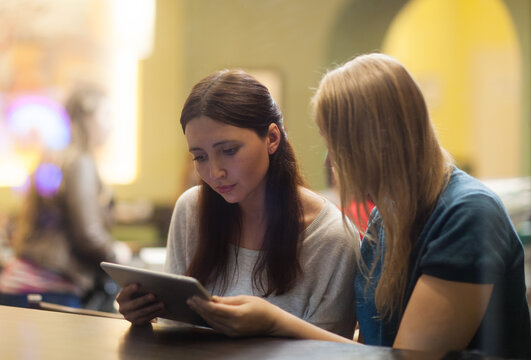 Two women in the restaurant using electronic tablet