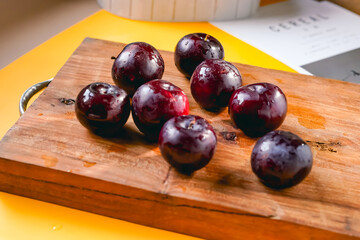 Fresh black plums on cutting board