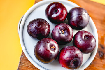 Fresh black plums on cutting board