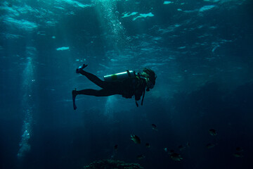 Woman scuba diver swimming in deep blue