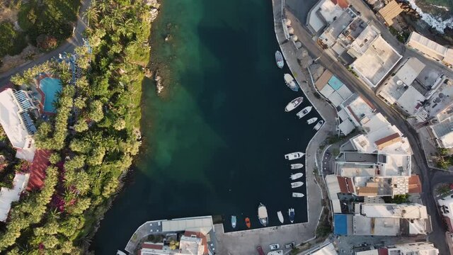 Aerial photography of beautiful greek island Crete and port with boat. Daylight. Aerial top view of city and boats in a blue water. 