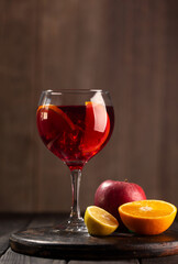 Sangria in glass with ingredients - orange, lemon and apple, dark wooden background