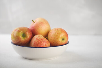 Bowl of ripe red apples on white background