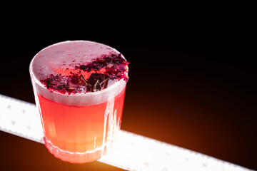 clover club cocktail drink with raspberry and rose petal on black background