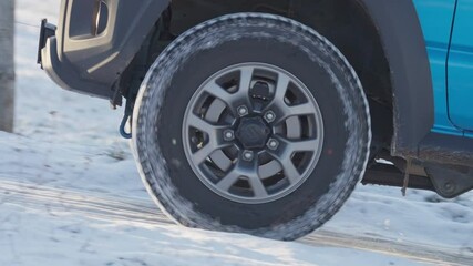 Close up of wheel spinning 4x4 off road jeep in snowy winter shot in 4k super slow motion