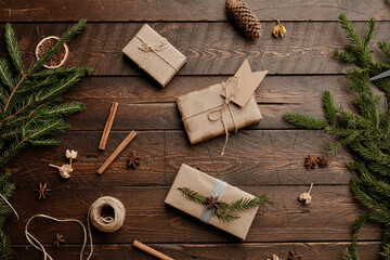 Top view Christmas background with craft presents at wooden table decorated with fir branches, copy space
