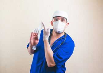 Fototapeta na wymiar Doctor with white glowes on hands in blue surgeon suit and protective breathing mask isolated