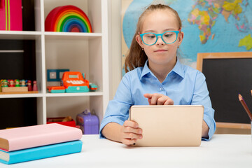 A girl with Down syndrome is studying online on an iPad