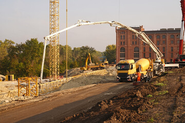 Truck-mounted concrete pump and concrete mixer truck filling concrete for base plate at a...