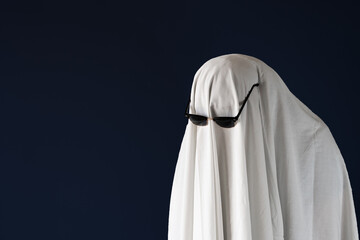 Sad person in Halloween costume of ghost with sunglasses