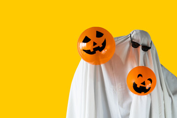 Person in Halloween costume of ghost with sunglasses and Jack-o'-lantern balloons smiling