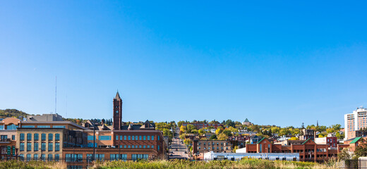 Panoramic view of downtown in autumn season with clear blue sky, view of transportation from the hill to the city. Daytime sightseeing of buildings and nature landscape. Skyline scenic with copy space