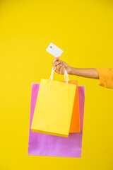 Mano de una mujer con bolsas de compra y una tarjeta para pagar