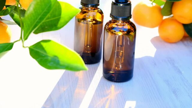  Mandarin oil. Citrus essential oil.Organic natural bio oil. oil in brown glass bottles and mandarin bushes in a sunny garden. 4k footage