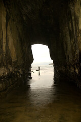 Person stands at the entrance to Cathedral Caves Sea Cave on the Caltins Coast South Island New Zealand.