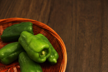 木製テーブルにあるザルの中の複数のピーマン