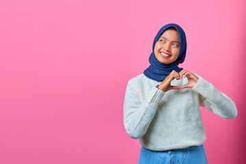 Obraz premium Portrait of smiling young Asian woman showing heart shape gesture with two hands