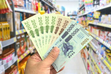 Taipei, Taiwan - Oct 11, 2021 : Man's hand hold the Quintuple Stimulus Voucher in a grocery store.