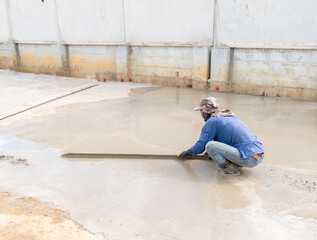 worker plastering cement on floor for road in factory.