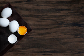 White hen eggs with an open appearing yolk, on dark background. Space for text.