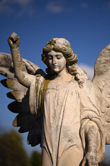 Photo of a weathered and worn sculpture of an angel, focused on the angel's downward looking face