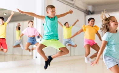 Foto auf Leinwand Young girls and boys jumping together in dance studio. © JackF