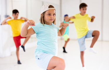 Girl in white cap dancing hip-hop with his mates during groung dance class.