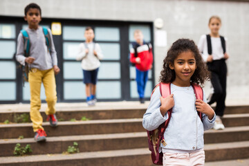 Portrait of african american preteen girl with rucksack walking outdoors on her way to school on warm autumn day. Back to school concept.