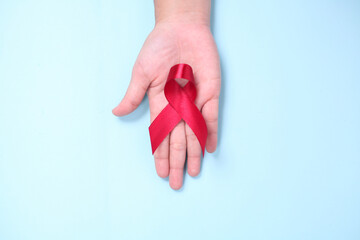 red ribbon in the palm of the symbol against HIV isolated on blue background