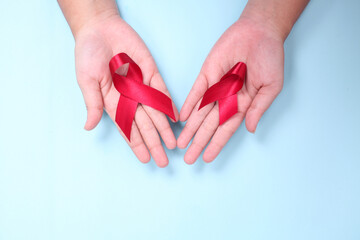 red ribbon in the palm of the symbol against HIV isolated on blue background