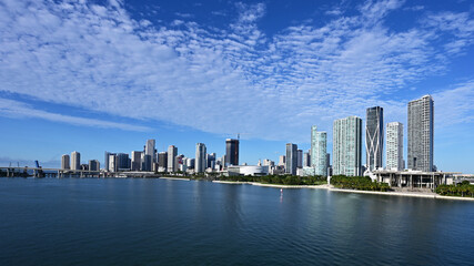 City of Miami, Florida skyline reflected in Biscayne Bay under sunny summer cloudscape.